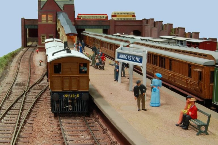 Abbotstone station platform with figures and a train arriving