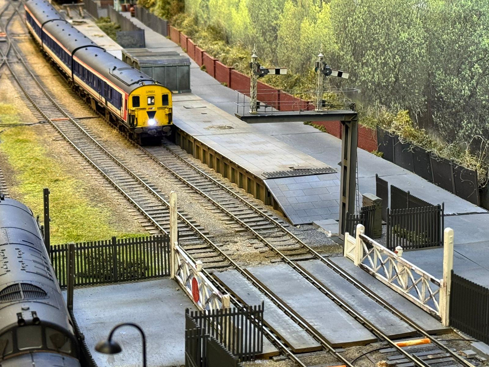 Network SouthEast diesel unit at the platform at Patrick Lane, beside the level crossing and semaphore signals