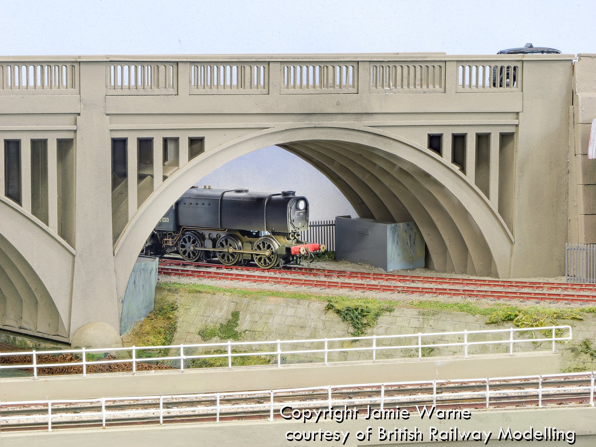 Steam locomotive framed beneath the concrete arch of the Redbridge causeway bridge