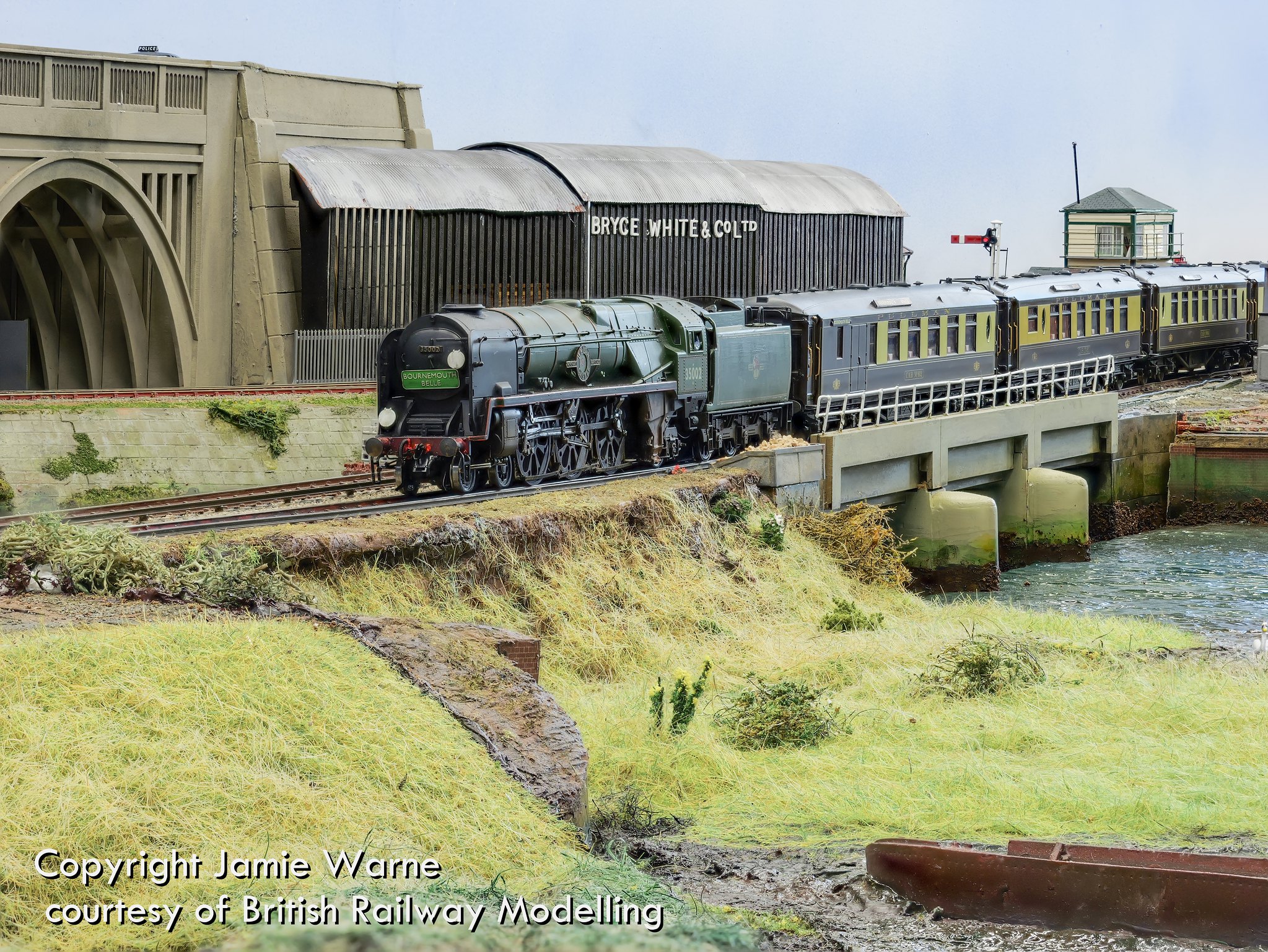 Rebuilt Bulleid Pacific in BR green leading green coaches across the causeway at Redbridge Wharf