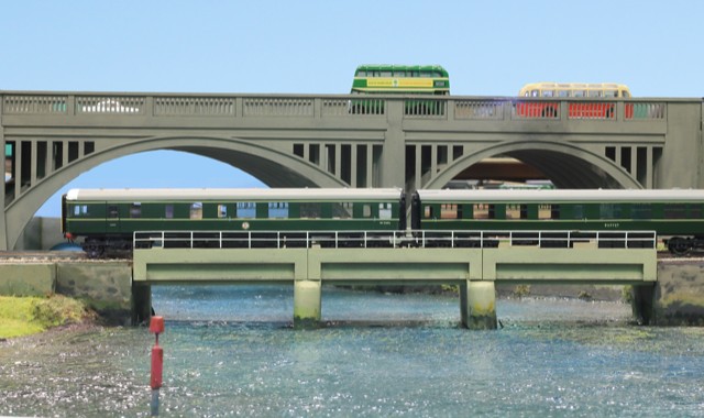 Green diesel multiple unit crossing the arched causeway bridge over the River Test