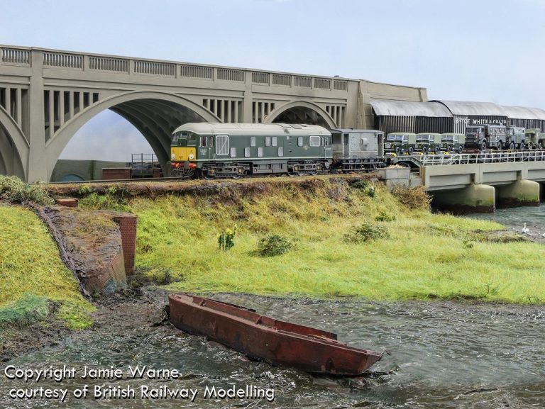 Green diesel locomotive on the causeway, with a boat beached on the mudflats