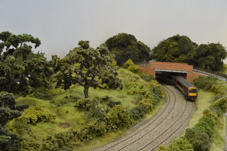 Train emerging from under the road bridge at Waton
